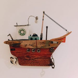 Escultura mural de barco artesanal Marengo. Casco de madera reciclada en tonos rojizos con cabina, bombilla y detalles de metal. Decoración náutica de pared de 50x40 cm.