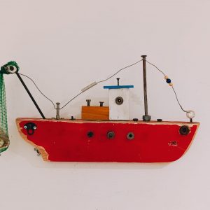 Escultura mural de barco pesquero artesanal Celsius. Casco de madera roja recuperada con red de pesca y conchas marinas. Arte de pared tridimensional de 45x25 cm.